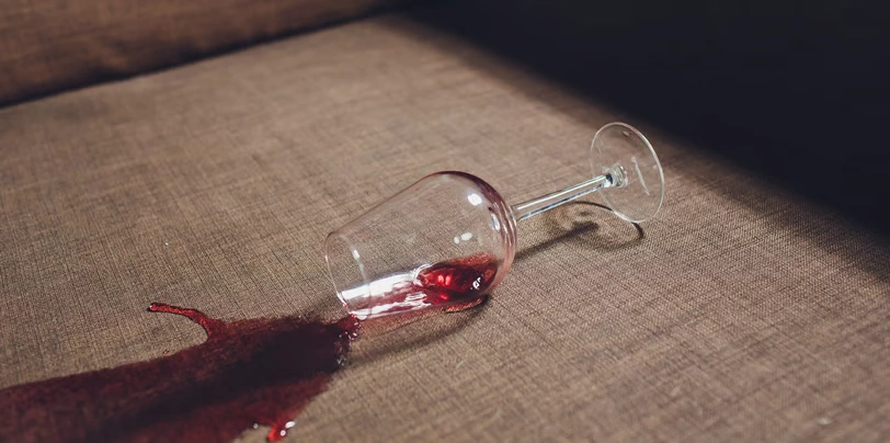 Copo de vinho derramado sobre tecido de estofado